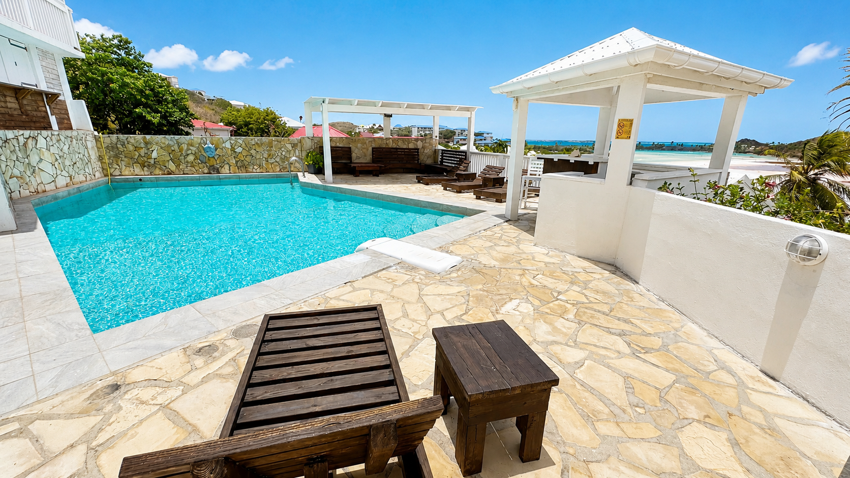 Terrasse piscine avec transats et vue sur la baie, résidence IDOLEM