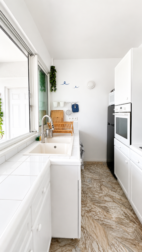 Cuisine équipée lumineuse avec grande fenêtre, studio Blanc Bleu Saint-Martin