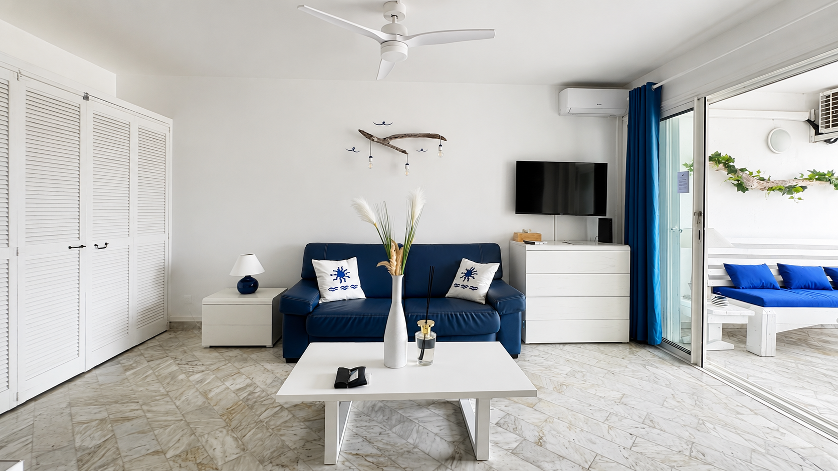 Séjour méditerranéen — canapé bleu marine, déco bois flotté et terrasse ouverte, studio Blanc Bleu